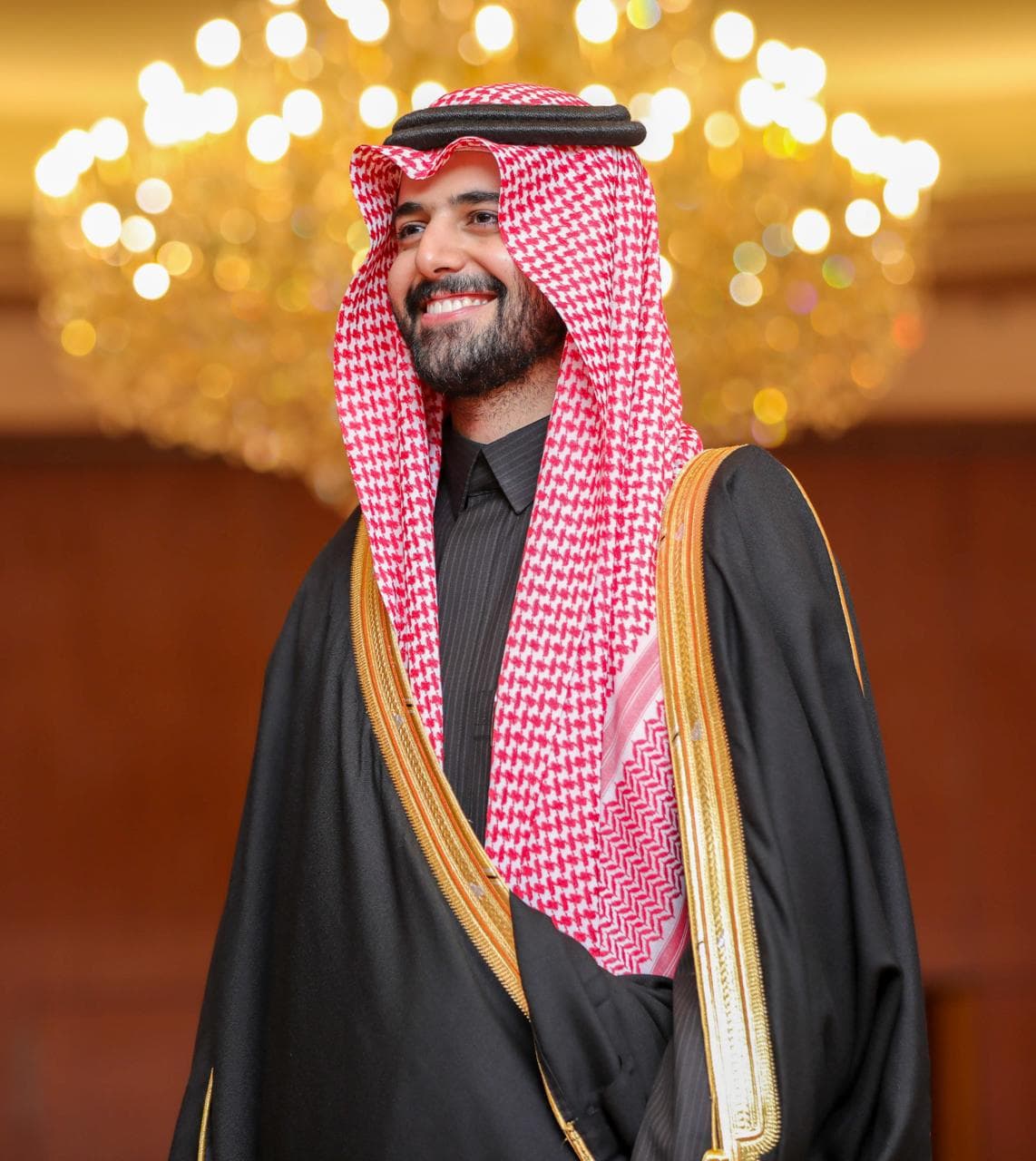 بورتريه قريب لعريس مبتسم أمام ثريا ذهبية